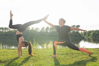 Sağlıklı yaşam tarzı ve insan kavramı - Esnek kadınlar yaz parkında yoga yapıyor