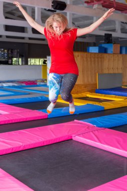 Fitness, eğlence, eğlence ve spor aktivite konsepti - Genç mutlu kadın kapalı bir trambolin üzerinde atlama