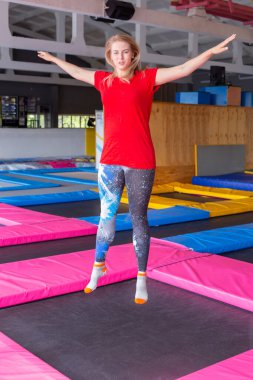 Fitness, eğlence, eğlence ve spor aktivite konsepti - Genç mutlu kadın kapalı bir trambolin üzerinde atlama
