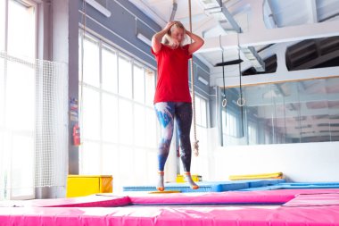 Fitness, eğlence, eğlence ve spor aktivite konsepti - Genç mutlu kadın kapalı bir trambolin üzerinde atlama