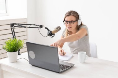 Radyo, dj, blogger ve insan kavramı - genç kadın sunucu radyo stüdyosunda çalışan ve mikrofon üzerinde konuşurken