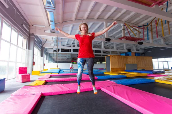 Koncepcja aktywności fizycznej, zabawy, wypoczynku i sportu-młoda szczęśliwa kobieta Skacząca na trampolinie w pomieszczeniu — Zdjęcie stockowe