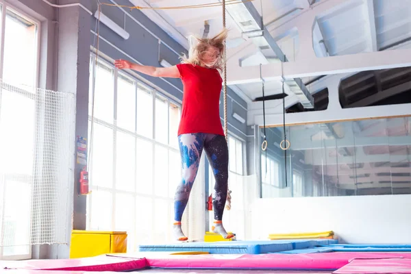 Fitness, diversión, ocio y deporte concepto de actividad - Mujer feliz joven saltando en un trampolín en el interior — Foto de Stock