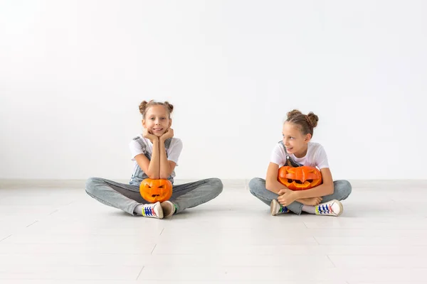 Buon Halloween, vacanze e concetto di infanzia - Carino gemelle sorelle ragazze con una zucca Jack-o-lanterna divertirsi mentre trascorre del tempo in casa — Foto Stock