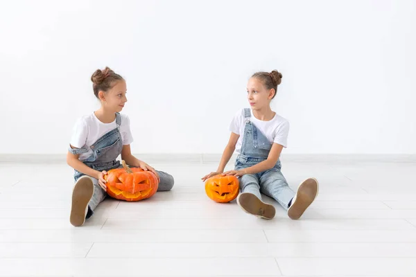 Šťastný Halloween, prázdniny a dětství koncept - roztomilé malé dvojčata sestry dívky s dýně Jack-o-lucerna baví při trávení času uvnitř — Stock fotografie