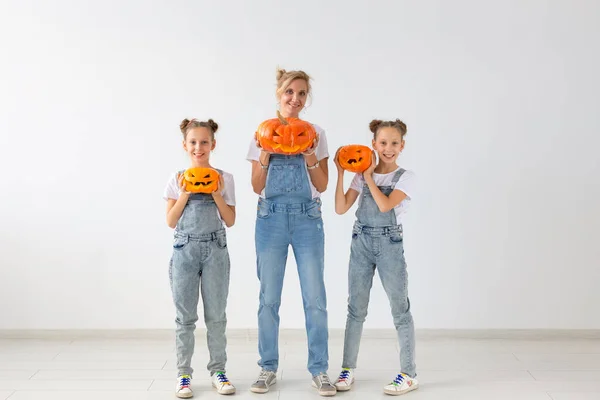 Buon Halloween e le vacanze concetto - Una madre e le sue figlie con le zucche. Famiglia felice che si prepara per Halloween . — Foto Stock