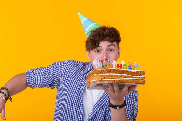 Vicces pozitív fickó tartja a kezében egy házi torta a felirat boldog születésnapot pózol a sárga háttér. Az ünnepek és az évfordulók fogalma. — Stock Fotó