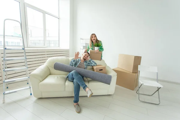 Satisfeito jovem casal alegre homem forte e mulher bonita segurando suas coisas em suas mãos sentado na sala de estar de um novo apartamento. Conceito de aquecimento doméstico . — Fotografia de Stock