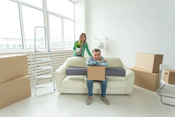 Jovem casal alegre se alegra em se mudar para uma nova casa que estabelece seus pertences na sala de estar. Conceito de aquecimento doméstico e hipotecas para uma família jovem — Fotografia de Stock