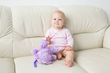 Çocuklar, bebek ve çocukluk konsepti - Güzel sevimli yumuşak bebek kanepede oturan