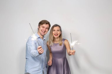 Parti, kutlama, yeni yıl, etkinlik ve tatil konsepti - mavi gömlekli adam ve mor elbiseli kadın elinde bir havai fişek sopası