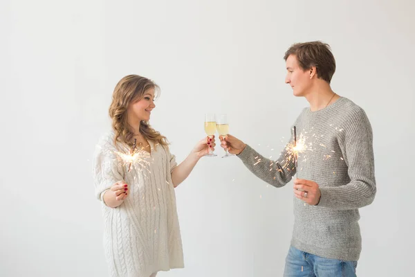 Ano Novo, feriados, data e dia dos namorados conceito - casal amoroso segurando faíscas luz e copos de champanhe sobre fundo branco com espaço de cópia — Fotografia de Stock