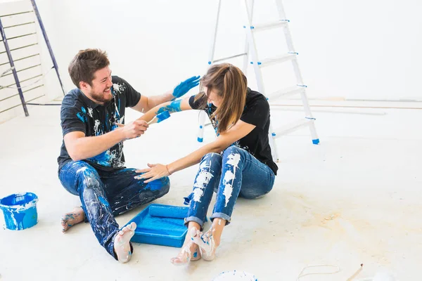 Renovación, redecoración y concepto familiar - Pareja joven verter pintura y divertirse — Foto de Stock