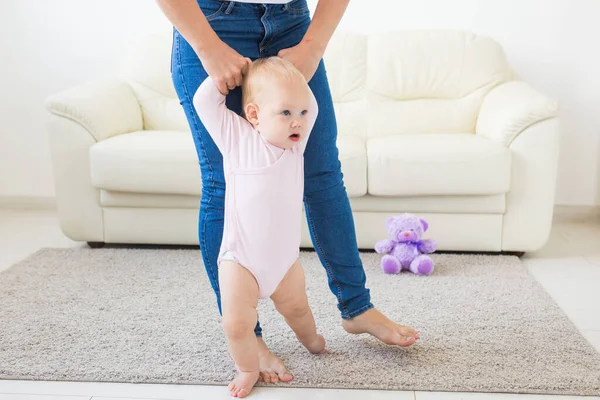 First steps of baby toddler learning to walk in white sunny living room. Footwear for child. — Stock Photo, Image