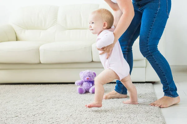 Bebê dando os primeiros passos com as mães ajuda em casa — Fotografia de Stock