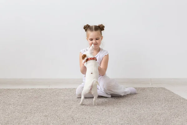 Concepto de perros, niños y mascotas - niña pequeña sentada en el suelo con un lindo cachorro — Foto de Stock