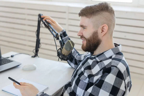 Radio, dj, blogger and people concept - presentador joven trabajando en el estudio de radio y hablando por el micrófono — Foto de Stock