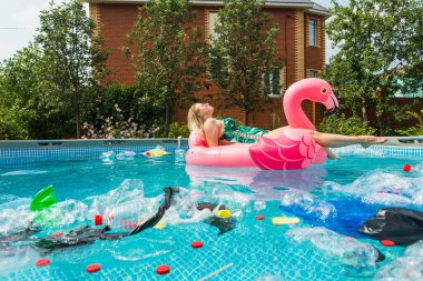 Çöp sorunu, plastik geri dönüşüm, kirlilik ve çevre kavramı - aptal kadın yüzer ve kirli bir havuzda eğlenin. Şişeler ve plastik torbalar onun yanında yüzer.