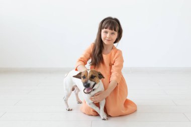 Çocuklar ve evcil hayvan sahibi kavramı - küçük çocuk kız sevimli köpek Jack Russell Terrier ile katta oturan