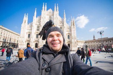 Kış seyahat, tatil ve kuşlar kavramı - selfie güvercinler yakınındaki Milan Katedrali Duomo di Milano, İtalya ile alarak genç komik adam.