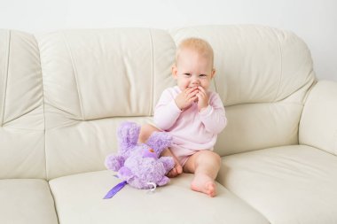 çocukluk, bebeklik ve insan kavramı - evde kanepede oturan mutlu küçük bebek kız