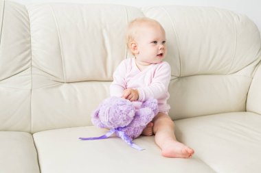 çocukluk, bebeklik ve insan kavramı - evde kanepede oturan mutlu küçük bebek kız