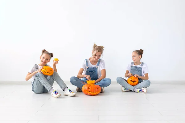 Buon Halloween e le vacanze concetto - Una madre e le sue figlie con le zucche. Famiglia felice che si prepara per Halloween . — Foto Stock