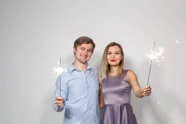 Festa, ano novo, Natal, família e feriados conceito - jovem casal segurando sparklers no fundo branco — Fotografia de Stock