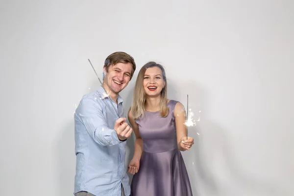 Festa, ano novo, Natal, e feriados conceito - jovem casal segurando sparklers no fundo branco — Fotografia de Stock