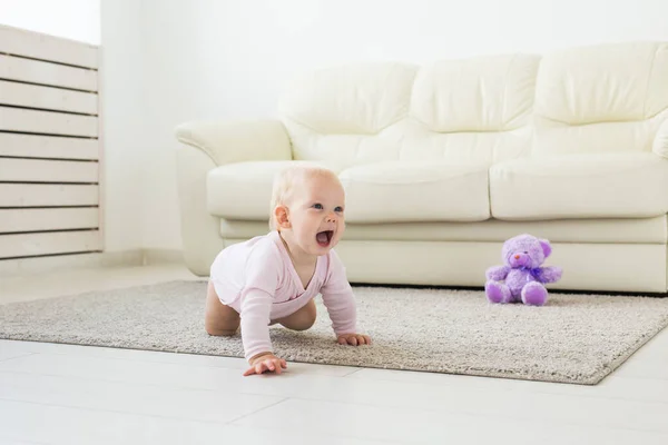 Sonriente niña arrastrándose en casa en el suelo — Foto de Stock