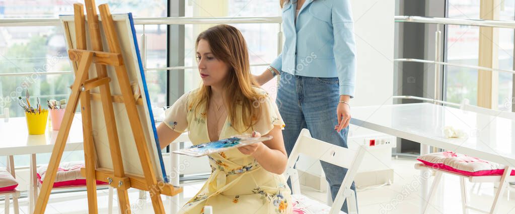 School of art, college of arts, education for group of young students. Happy young woman smiling, girl learning to paint with teacher.