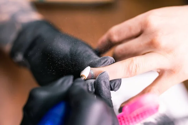 Női mester használ egy elektromos gép, hogy távolítsa el a körömlakk során manikűr a szalonban. Egy közeli hardver manikűr. A kézápolás fogalma. Női manikűrös körömtisztítás marógéppel — Stock Fotó