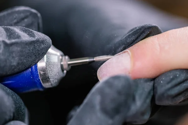 Manicure use broca elétrica de arquivo de unhas no salão de beleza. unhas perfeitas processo de manicure fechar-se com detritos voadores explosão . — Fotografia de Stock