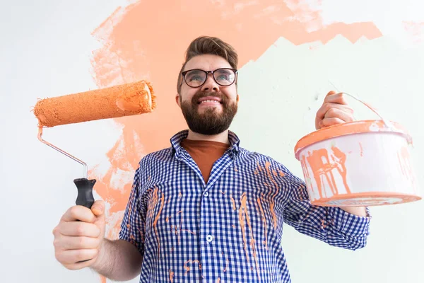 Male painting the wall with paint roller. Portrait of a funny guy painting wall in her new apartment. Redecoration and renovation concept — Stock Photo, Image