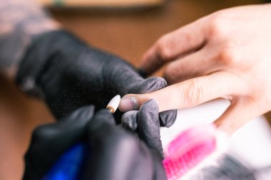 Jel cilasını çıkarmak için nalbur değirmenciliğine yakın çekim. Güzellik salonunda alet manikürü. Elektrikli çivi matkabı olan manikürcü eski jeli müşteri çivilerinden sökmüş. Eski Shillac 'ı değiştirme süreci.