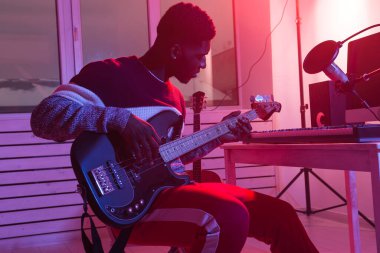 Müzik ve kayıt stüdyosu konsepti yaratmak - Afrikalı Amerikalı gitarist ev stüdyosunda elektro bas gitar kaydı yapıyor.