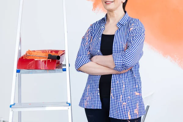 Close-up van de vrouw van middelbare leeftijd die de muur schildert met verfroller. Portret van een mooie jonge vrouw die een muur schildert in haar nieuwe appartement. Opknappen en renoveren. — Stockfoto