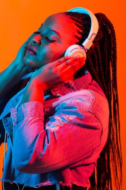 Kulaklıkla müzik dinleyen Afrikalı genç bir kadının neon portresi..