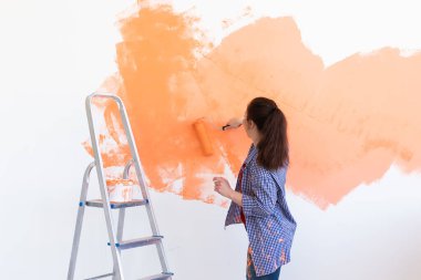 Kapalı mekanda boya pateniyle güzel bir bayan. Dekorasyon, yenileme, apartman onarımı ve ferahlatıcı konsept.