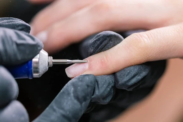 Manicure z bliska. Przygotowanie do manicure sprzętowego. Kosmetyk w gumowych rękawiczkach tnie naskórek i przetwarza paznokcie. — Zdjęcie stockowe