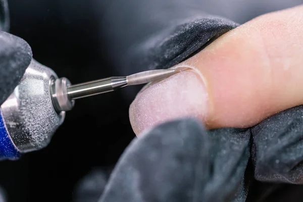 Detailní záběr hardwarové manikúry v salónu krásy. Manikérka aplikuje elektrický pilník na manikúru ženských prstů. — Stock fotografie
