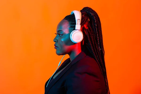 Africká americká mladá žena poslouchající hudbu on-line tanec a zpěv se sluchátky, neonové světlo. Koncept hudby a technologie. — Stock fotografie