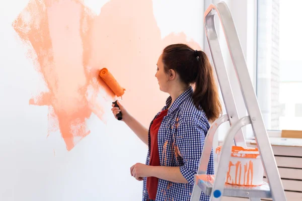 Bella donna pittura muro nel suo nuovo appartamento. Concetto di ristrutturazione e ridecorazione. — Foto Stock