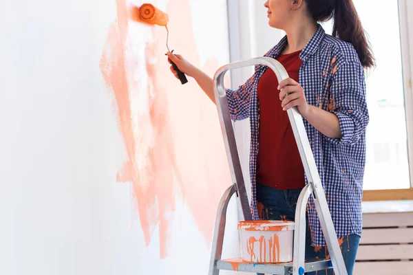 Cerca de la mujer pintando la pared interior del hogar. Concepto de renovación, reparación y redecoración . — Foto de Stock