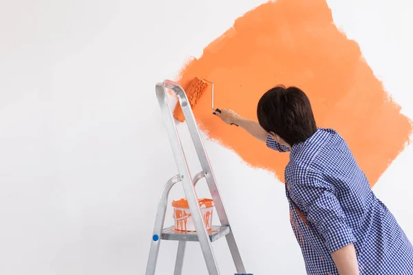 Bella donna di mezza età dipingere la parete con rullo di vernice. Ritratto di una giovane bella donna che dipinge un muro nel suo nuovo appartamento. Concetto di ristrutturazione e riqualificazione. — Foto Stock