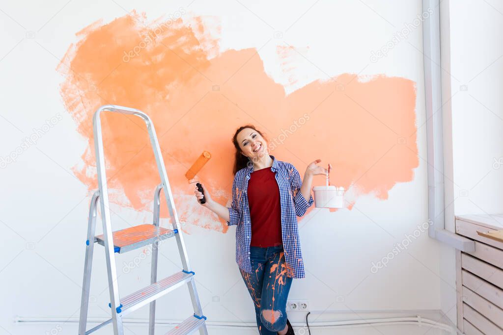 Pretty young woman with painting roller indoors. Redecoration, renovation, apartment repair and refreshment concept.