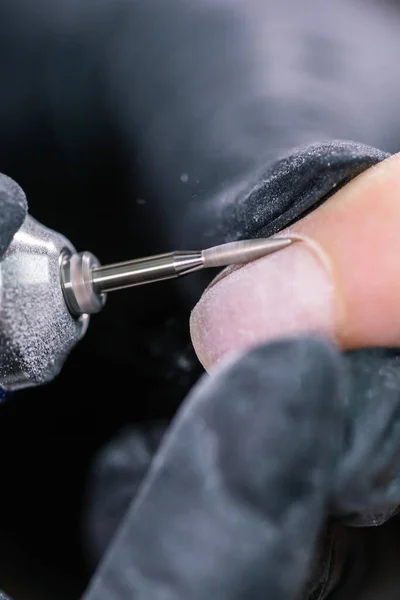 Processo manicure primo piano. Preparazione per la manicure hardware. Estetista in guanti di gomma taglia la cuticola ed elabora unghie. — Foto Stock