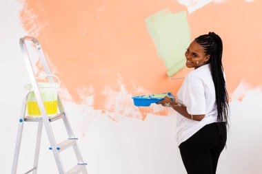 Kapalı alanda paten çizen güzel, Afro-Amerikan bir kadın. Dekorasyon, yenileme, apartman onarımı ve ferahlatıcı konsept.