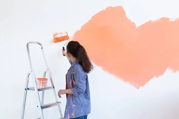 Felice giovane donna pittura muro nel suo nuovo appartamento. Concetto di ristrutturazione, ridecorazione e riparazione. Copia spazio . — Foto Stock