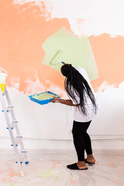 Felice donna afroamericana pittura muro nel suo nuovo appartamento. Concetto di ristrutturazione, ridecorazione e riparazione. — Foto Stock